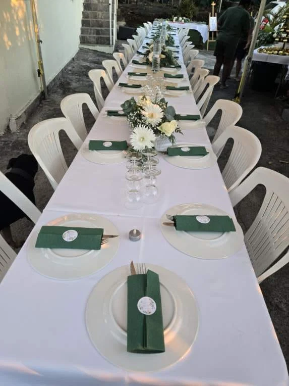 Une grande tablée avec chaises blanches et décoration florale